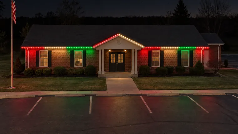A township hall at night with permanent roofline lighting set to christmas