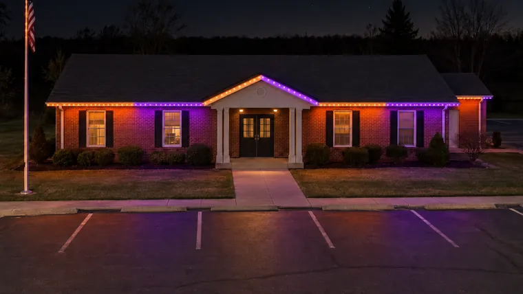 A township hall at night with permanent roofline lighting set to halloween