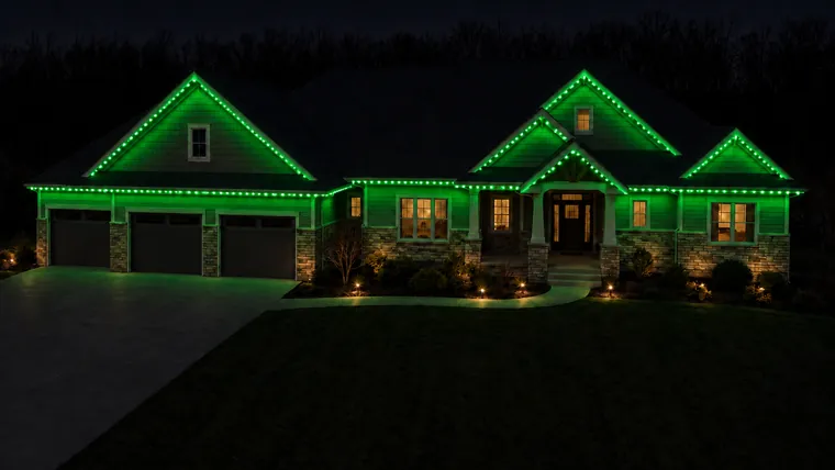A home at night with permanent roofline lighting set to st. patrick's